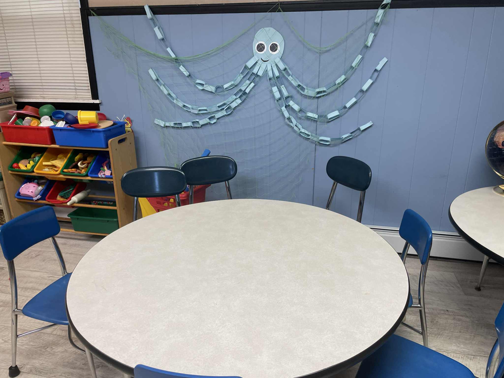 Classroom with round tables, blue chairs, and octopus wall decoration